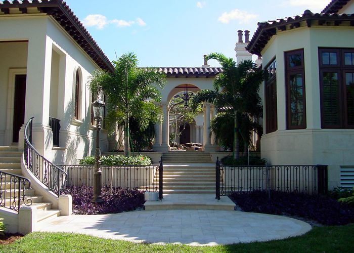 Mediterranean villa with cast stone arched gateway flanked by columns and palm trees