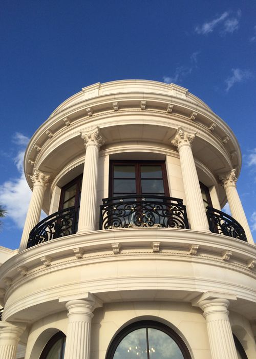 Circular rotunda turret with Corinthian cast stone columns, curved balustrade, and wrought iron balcony