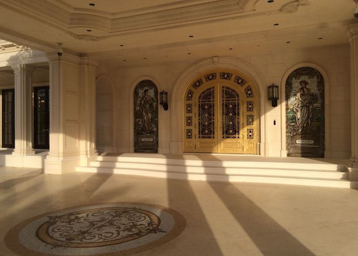 Grand interior porte-cochère with cast stone columns, arched niches, and marble flooring medallion